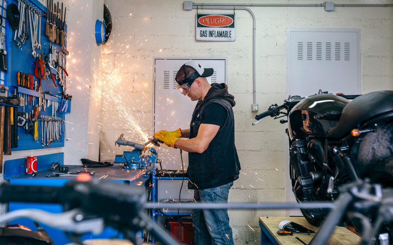 Man welding in a motorcycle workshop.