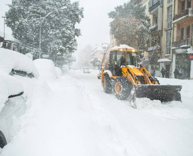 Snowplow clearing snow-covered urban street.