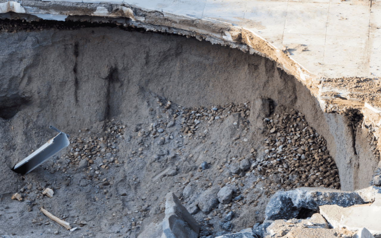 Large hole in concrete with gravel inside.